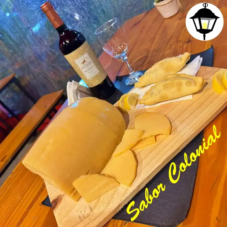 Empanadas rellenas de vacío braseado con queso provoleta, acompañadas de rodajas de limón y copa de vino tinto Malbec La Celia