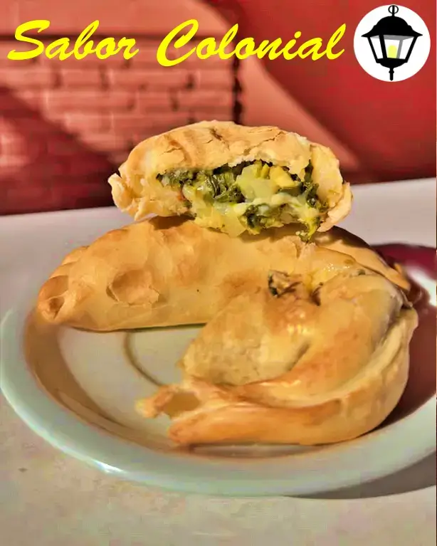 Empanadas vegetarianas gourmet rellenas de verduras frescas salteadas con hierbas aromáticas, presentadas con ensalada de hojas verdes.