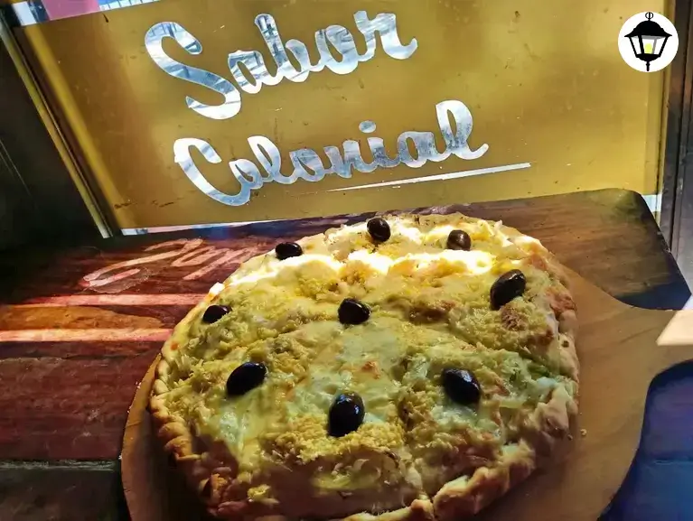 Fugazzeta rellena con queso mozzarella y cebolla, decorada con aceitunas negras